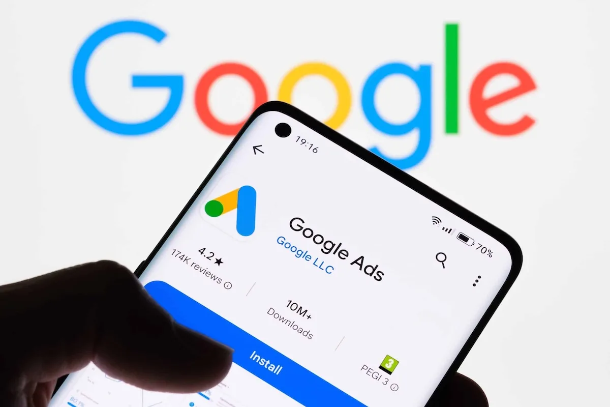 Smartphone mostrando la app de Google Ads frente al logo de Google — agencia certificada Google Partner operando bajo metodología One Search
